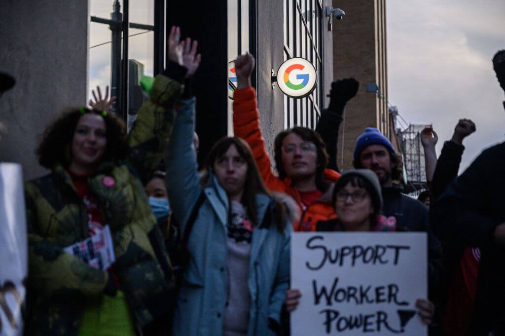 Photograph of workers rallying outside of Google offices in New York after recent layoffs with sign reading 