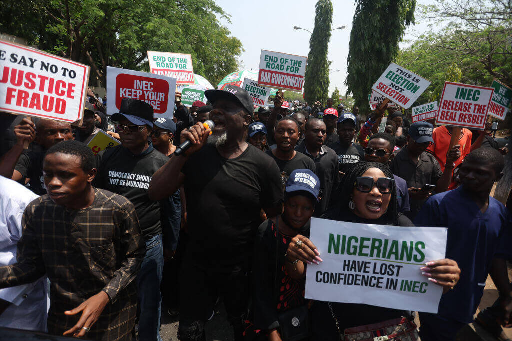 Photograph of supporters of Nigerians gathered with with signs to protest the contested election